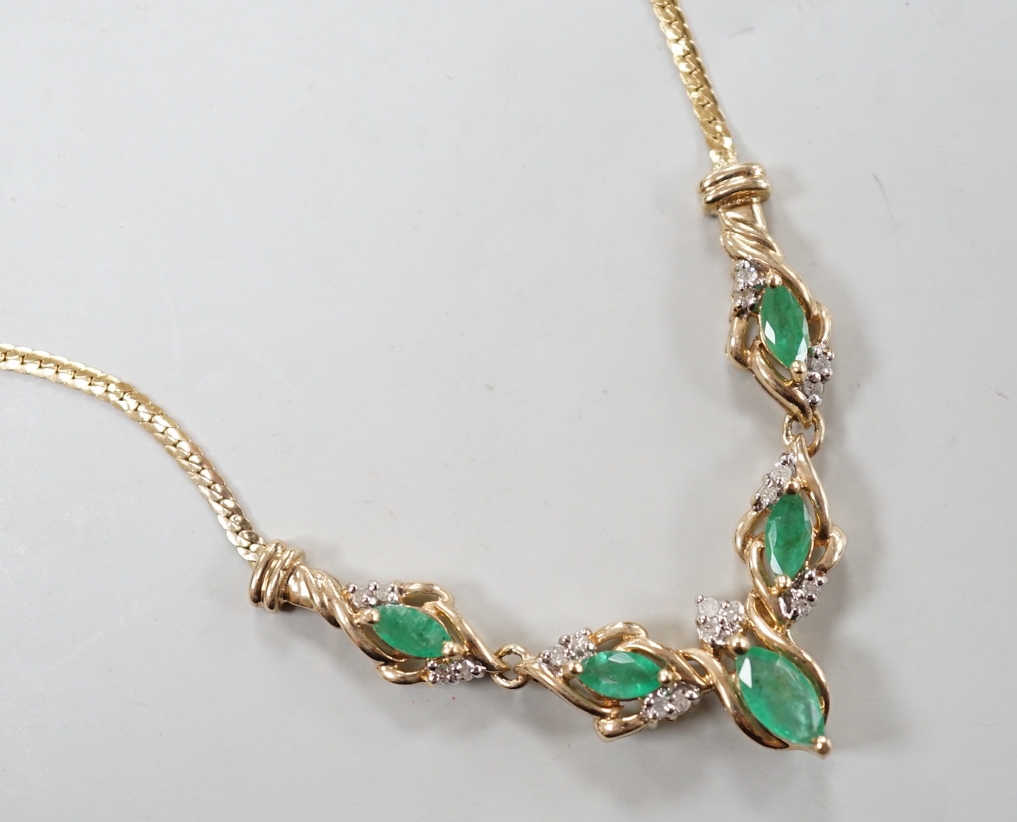 A modern 9ct gold, five stone marquise cut emerald and diamond chip cluster set necklace, 46cm, gross weight 6.2 grams.